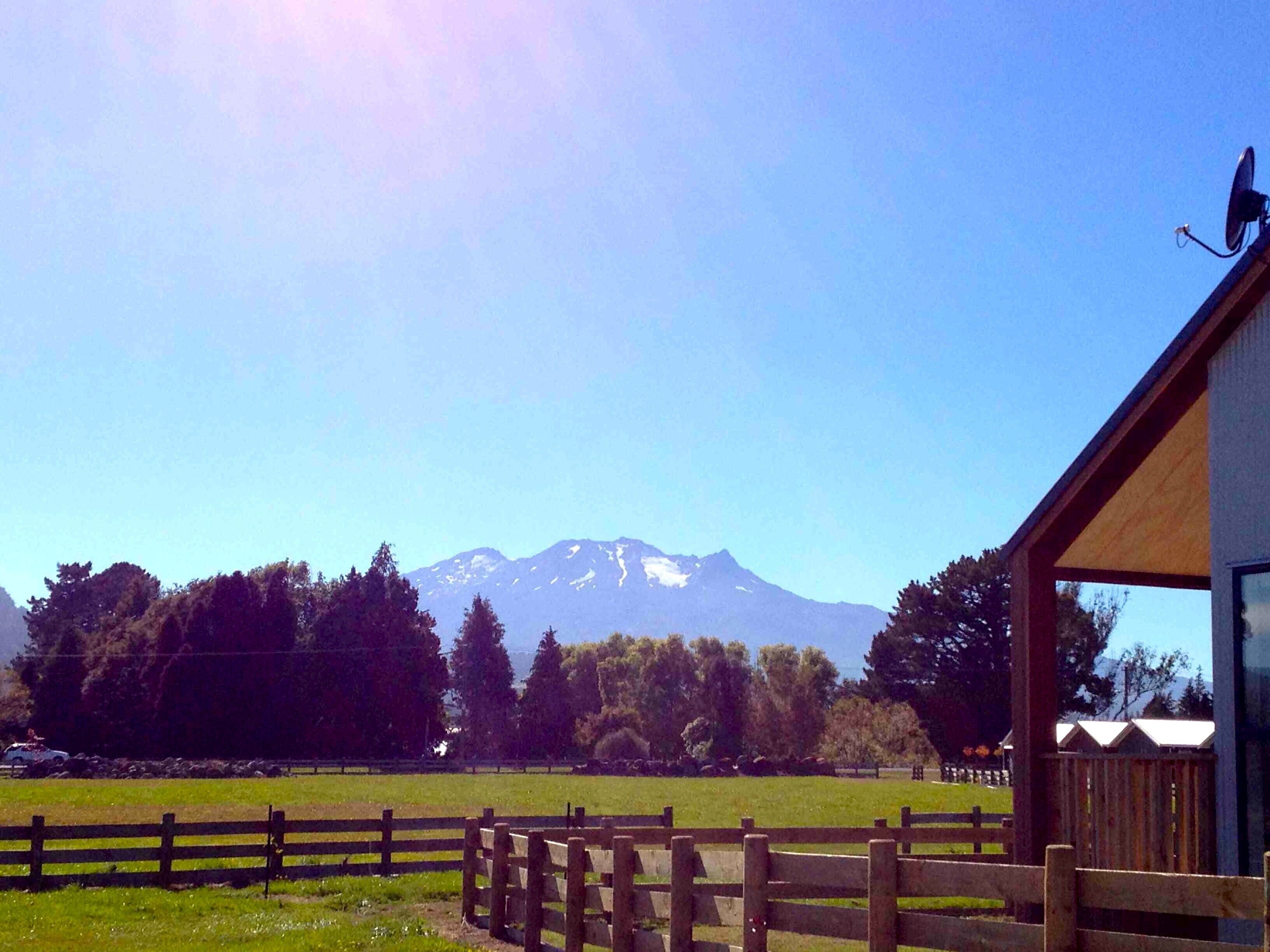 Une vue sur une montagne, prise depuis un bâtiment avec une clôture en bois au premier plan.