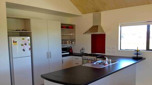 Uma cozinha moderna com uma ilha central, armários brancos, forno embutido e uma janela que oferece iluminação natural.