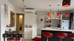 A modern kitchen with a central island, red bar stools, and pendant lighting. - Rooftop garden, Lakeview, 5 mins walk to town (Queenstown Hill)