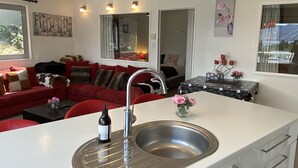 A compact living space with a kitchenette, red furniture, a sink, and a small dining area. - Rooftop garden, Lakeview, 5 mins walk to town (Queenstown Hill)