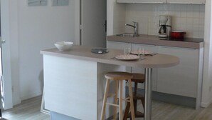 Una cocina moderna con una isla central, taburetes de bar, un fregadero y una lámpara en el techo.