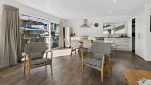A modern kitchen with white cabinets, a large island, and a dining area with two patterned chairs and a table.