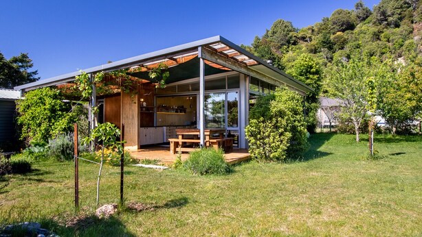 Una casa moderna con un porche cubierto, una terraza de madera y un jardín.
