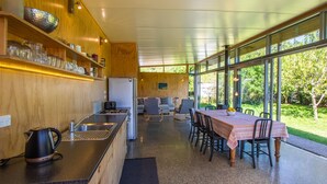 Una cocina moderna con armarios de madera, un lavamanos de acero inoxidable y un comedor con mesa y sillas.