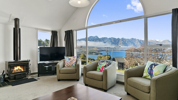 Una sala de estar con chimenea, dos sillones, una mesita de centro y un ventanal con vistas a la montaña.