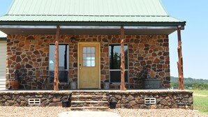 A stone building with a green roof, a yellow door, and a porch with outdoor furniture. - Rustic Loyal Valley Private Guesthouse with Peace & Serenity Views (Mason)