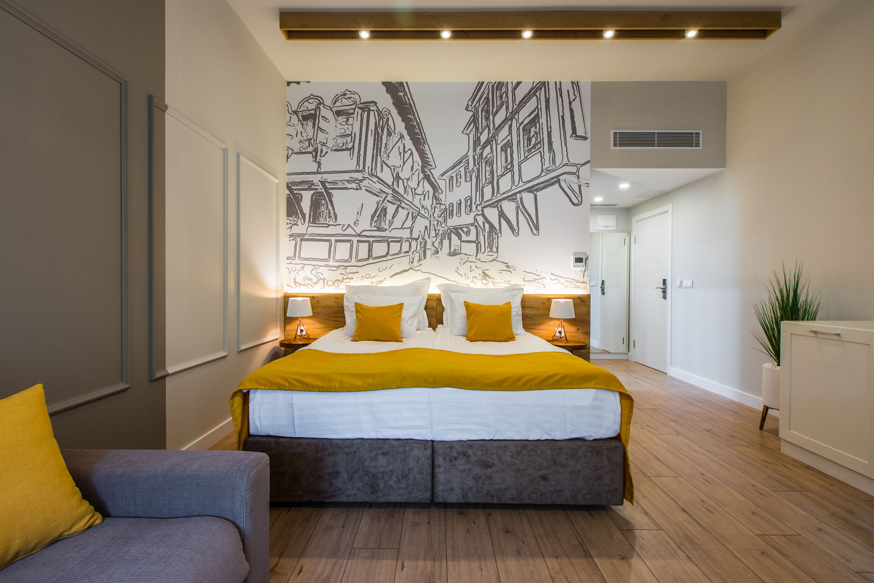 Une chambre moderne avec un grand lit, des lampes de chevet, une fresque murale et une plante.