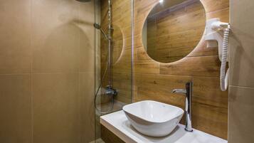 A modern bathroom with a white sink, a handheld showerhead, and a towel rack.