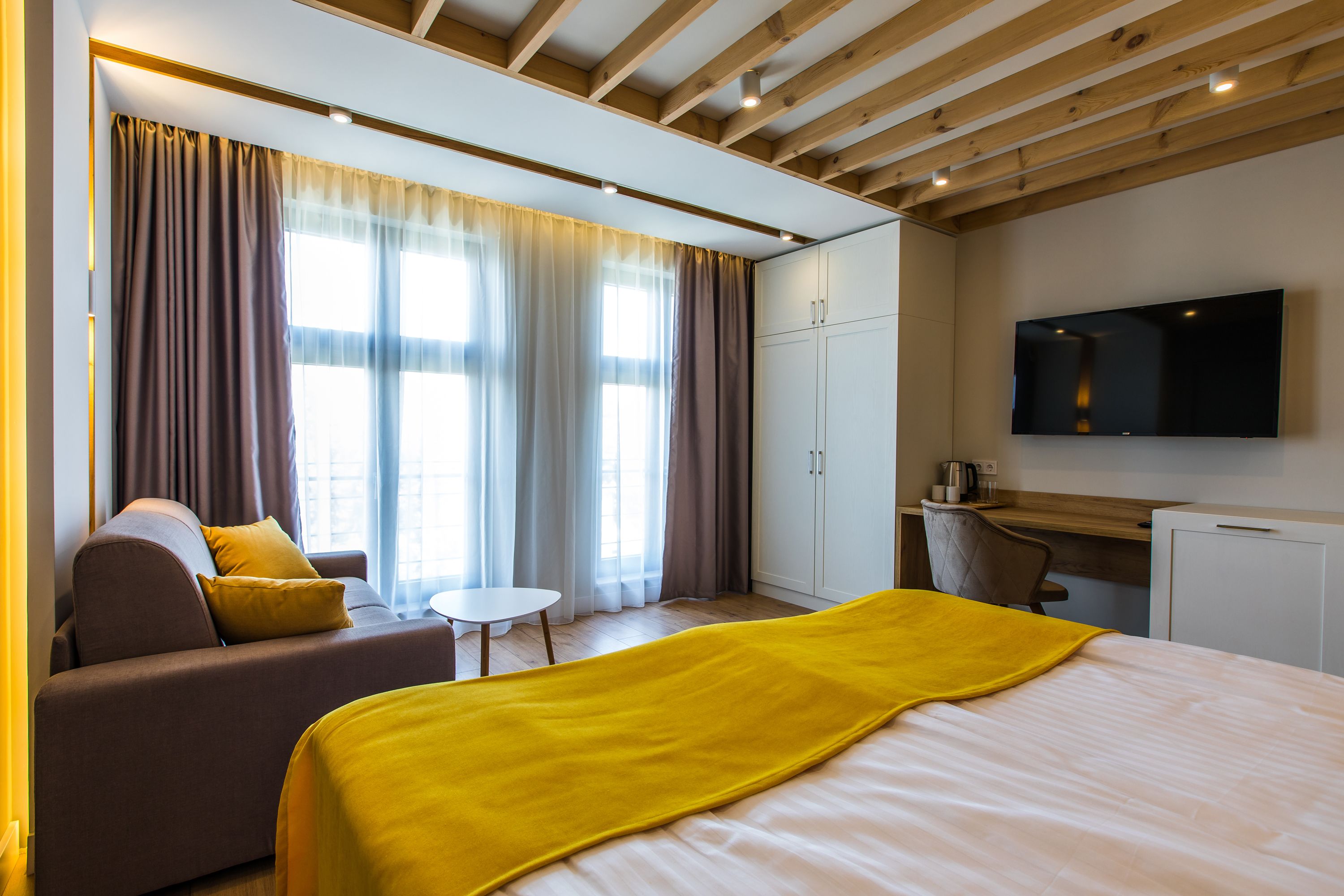 Una habitación de hotel moderna con una cama, un sofá, un escritorio y un televisor.