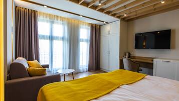 Una habitación de hotel moderna con una cama, un sofá, un escritorio y un televisor.