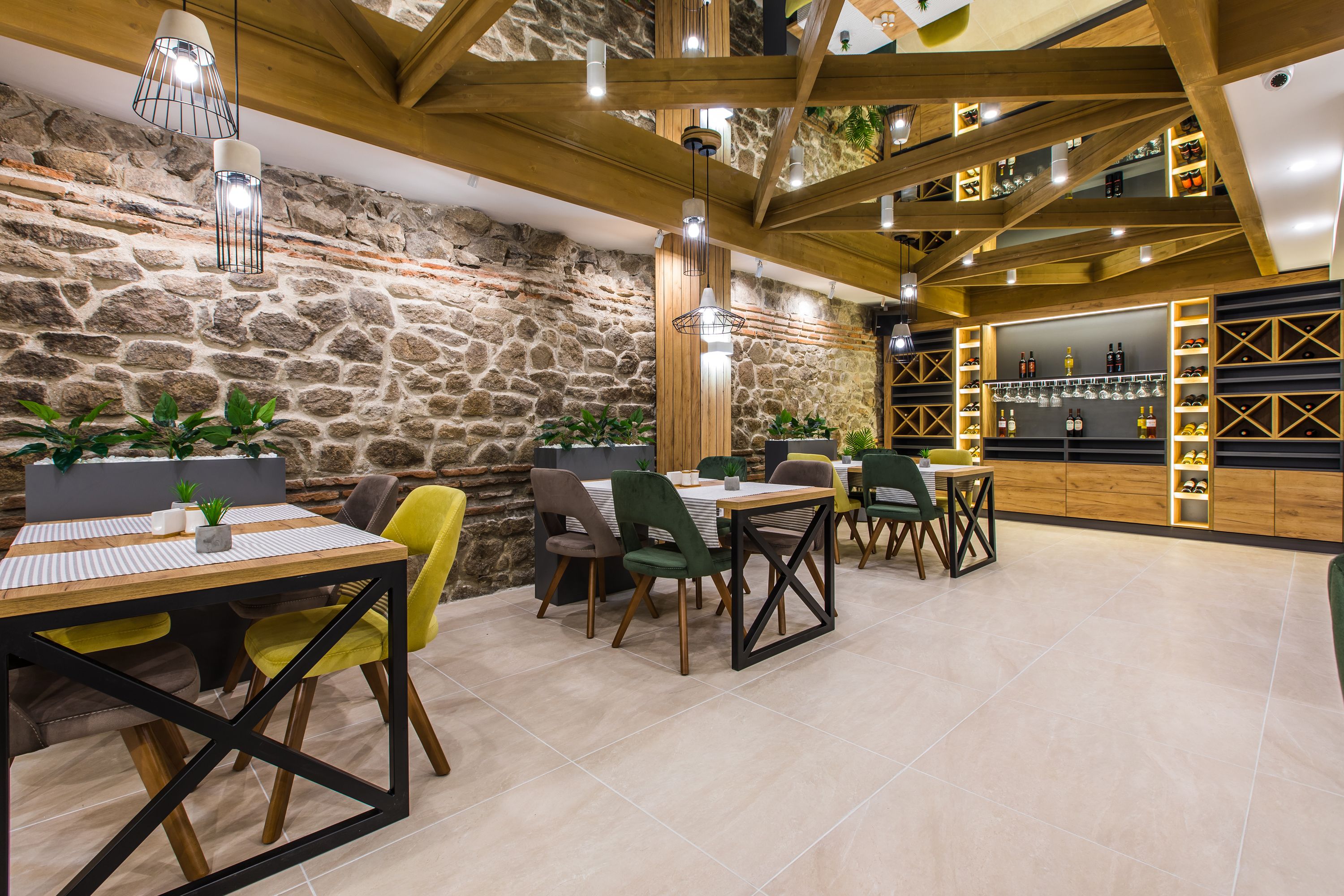 Restaurante com paredes de pedra, vigas de madeira e um bar com prateleiras cheias de garrafas e copos.