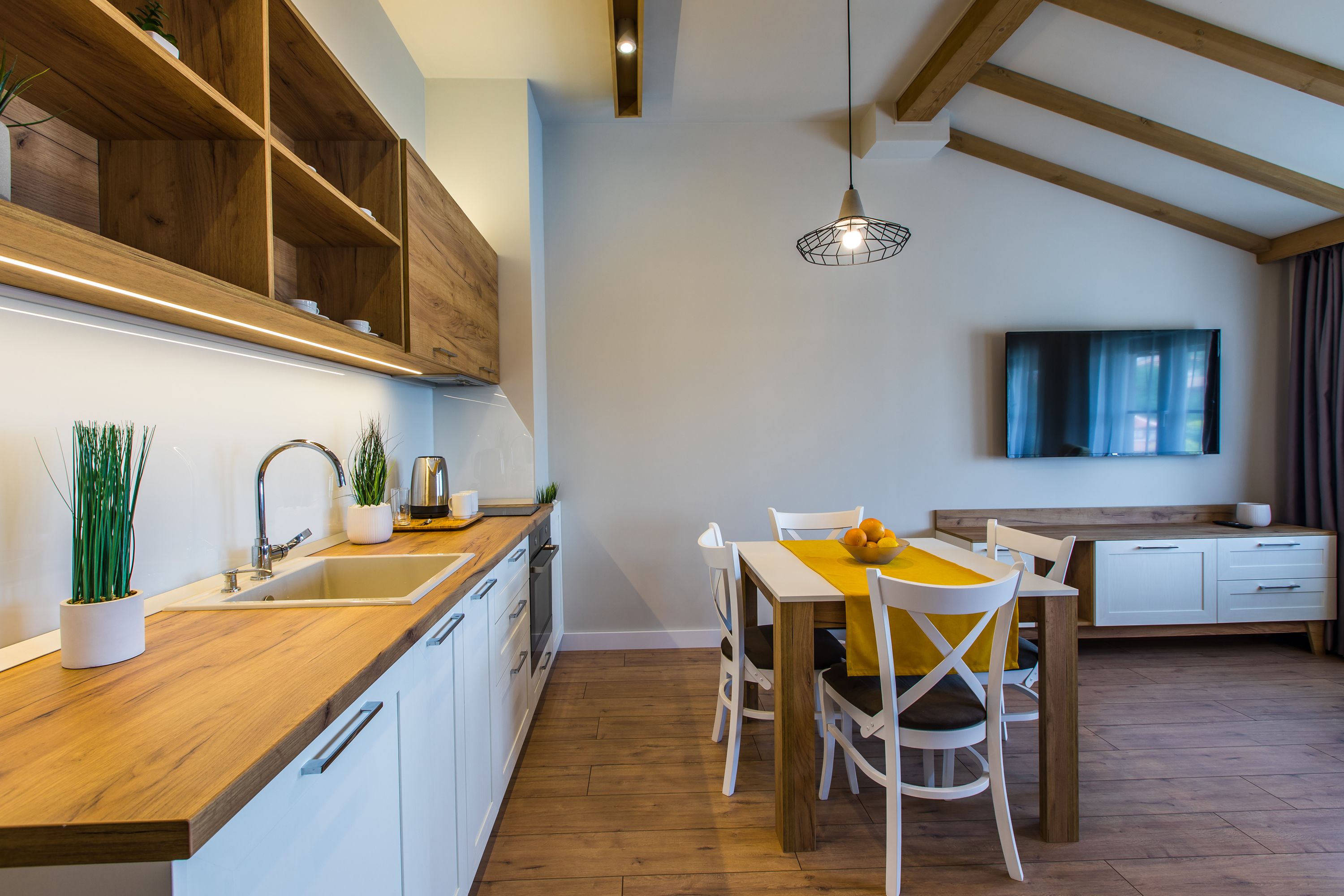 Una cocina moderna con armarios de madera, un lavabo y una zona de comedor con mesa y sillas.