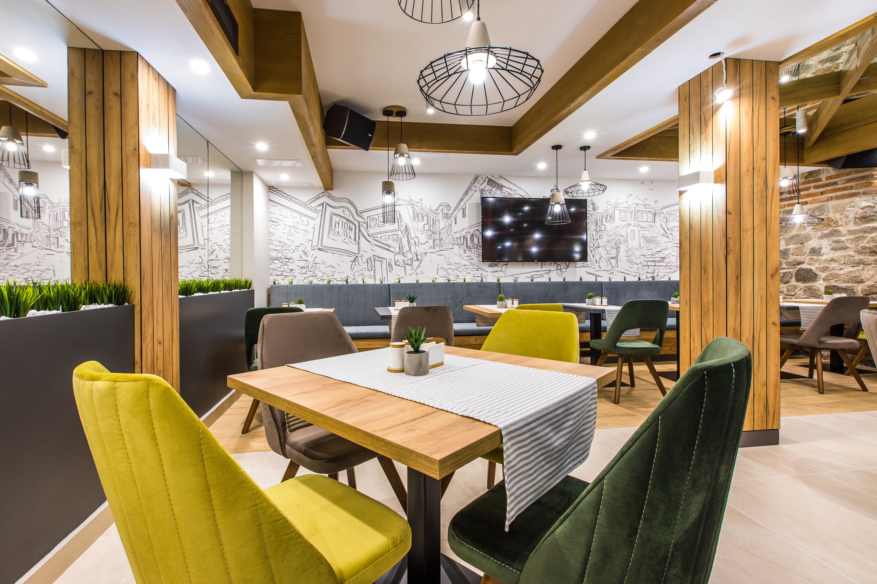 En modern restaurang med trädetaljer, en stor TV-skärm och färgglada stolar.