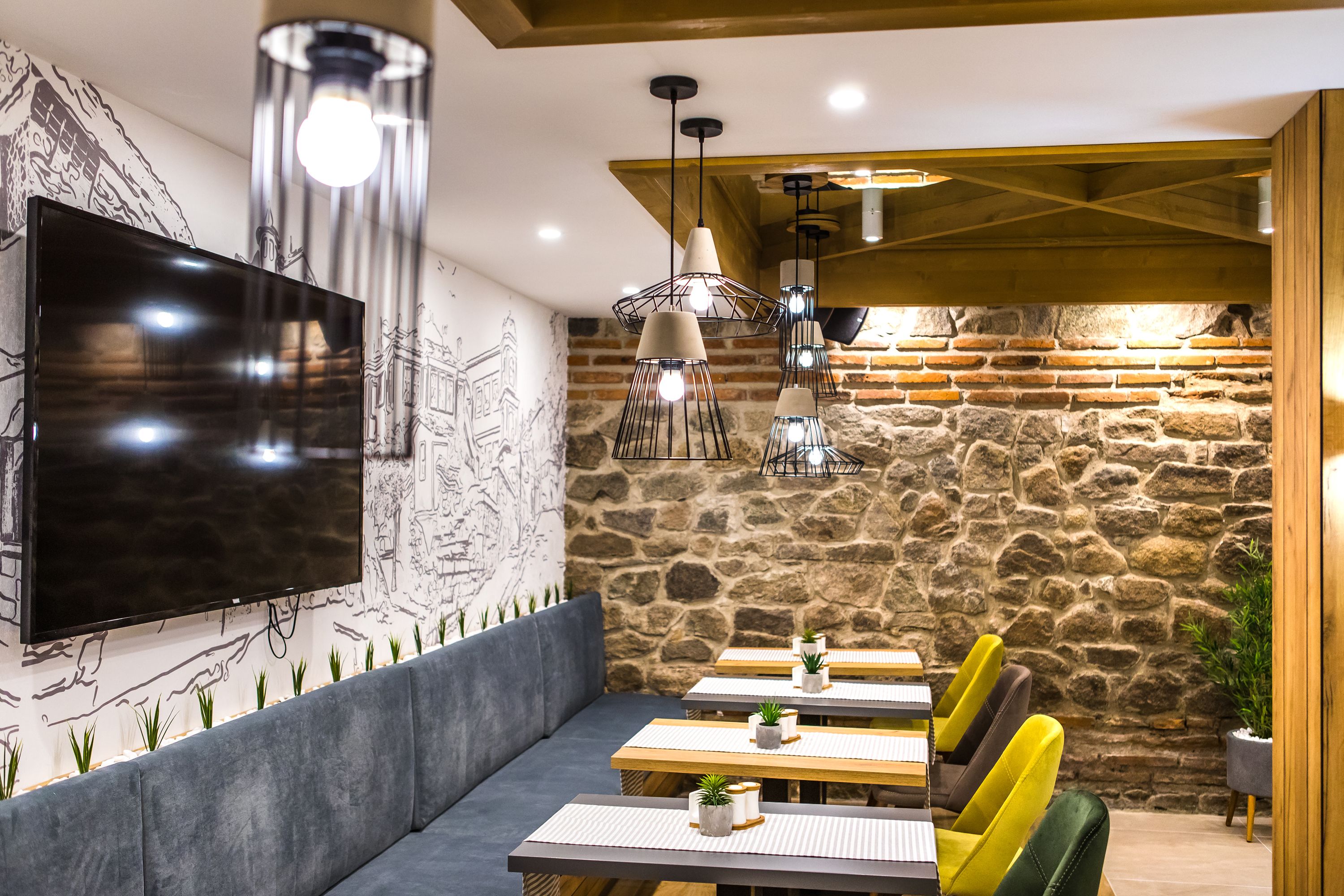 Un comedor moderno con pared de piedra, televisor de pantalla plana y luces colgantes.