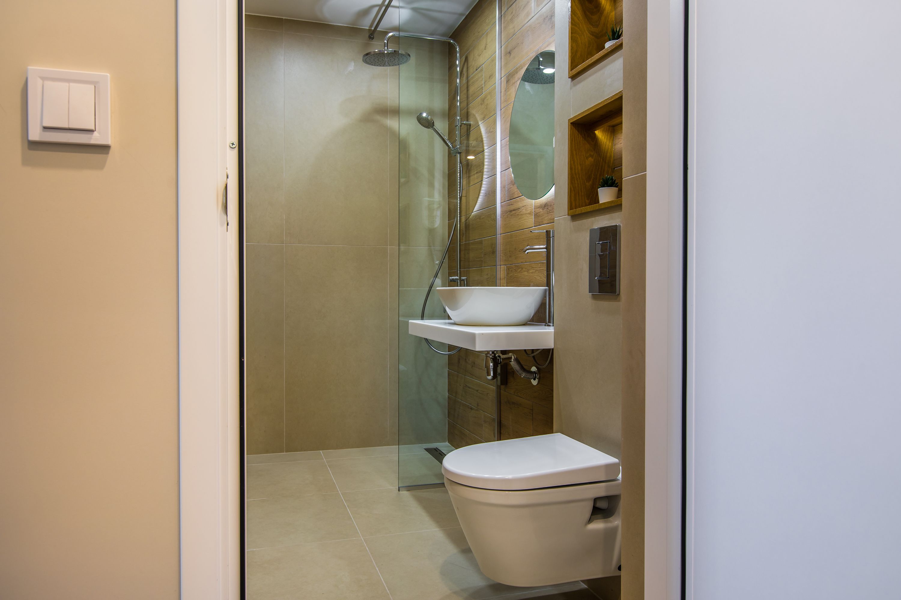 Un baño moderno con ducha envuelta en vidrio, un lavamanos blanco y un inodoro.
