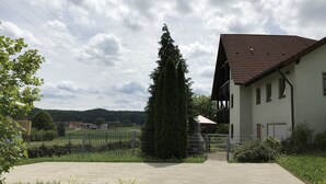 A residential building with a tiled roof, a paved driveway, and a fenced yard.