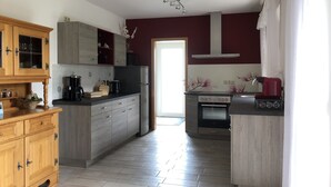 A modern kitchen with grey cabinets, a wooden cabinet with glass doors, a coffee maker, and a red espresso machine.