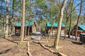 Un área boscosa con varias cabañas de madera con techos verdes, rodeada de altos árboles.