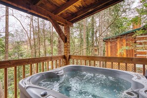 A hot tub on a wooden deck with a forest backdrop.