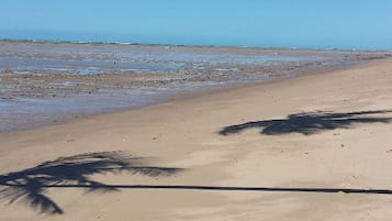 Perto da praia, areia branca, espreguiçadeiras, guarda-sóis