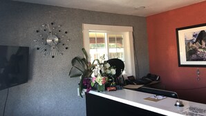 Una reception con una scrivania, un orologio, un quadro incorniciato e una finestra che si affaccia sul verde.