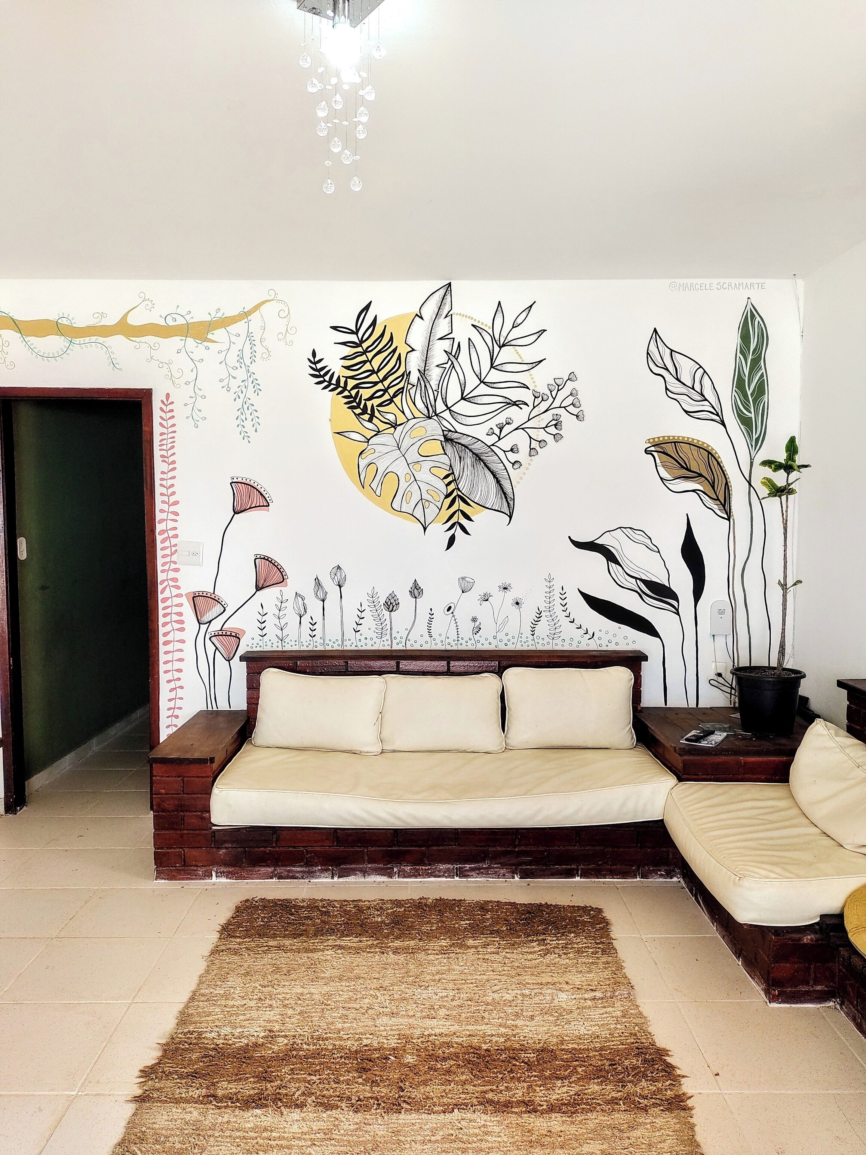 A living room with a sofa, a rug, and a wall mural of plants and flowers.