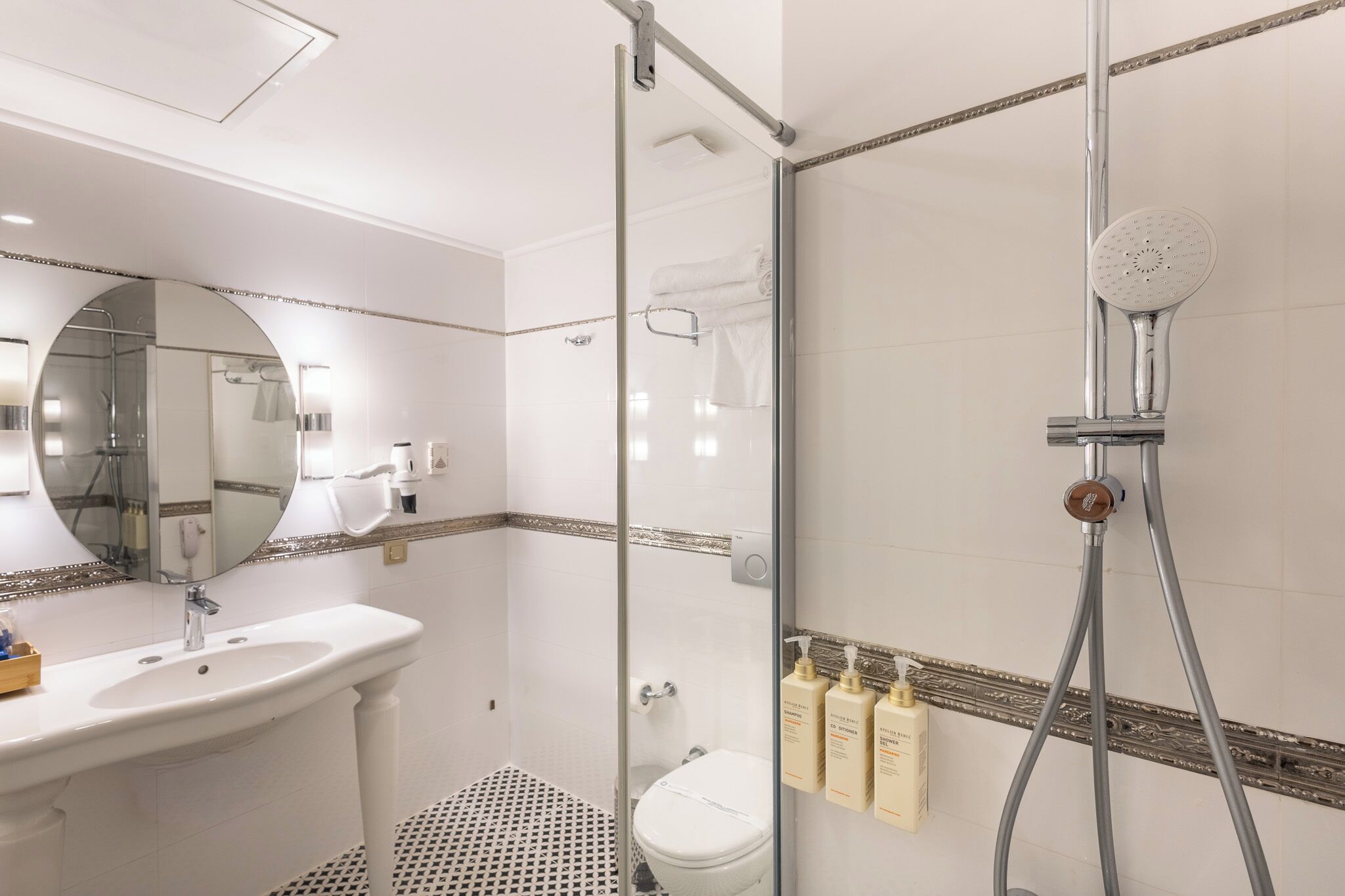 A bathroom with a glass-enclosed shower, a sink, a toilet, and a mirror.