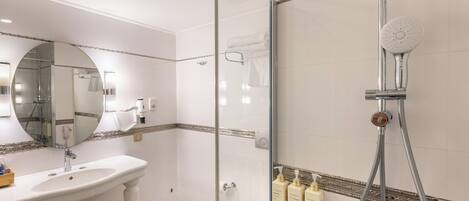 A bathroom with a glass-enclosed shower, a sink, a toilet, and a mirror.