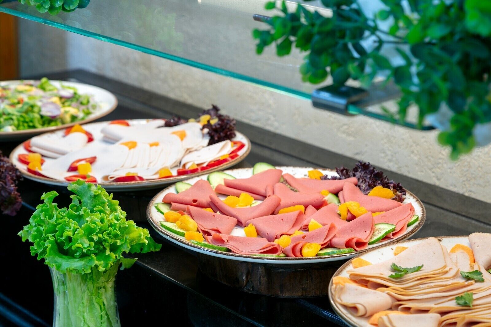 A buffet with various food items including sliced meats, vegetables, and garnishes.