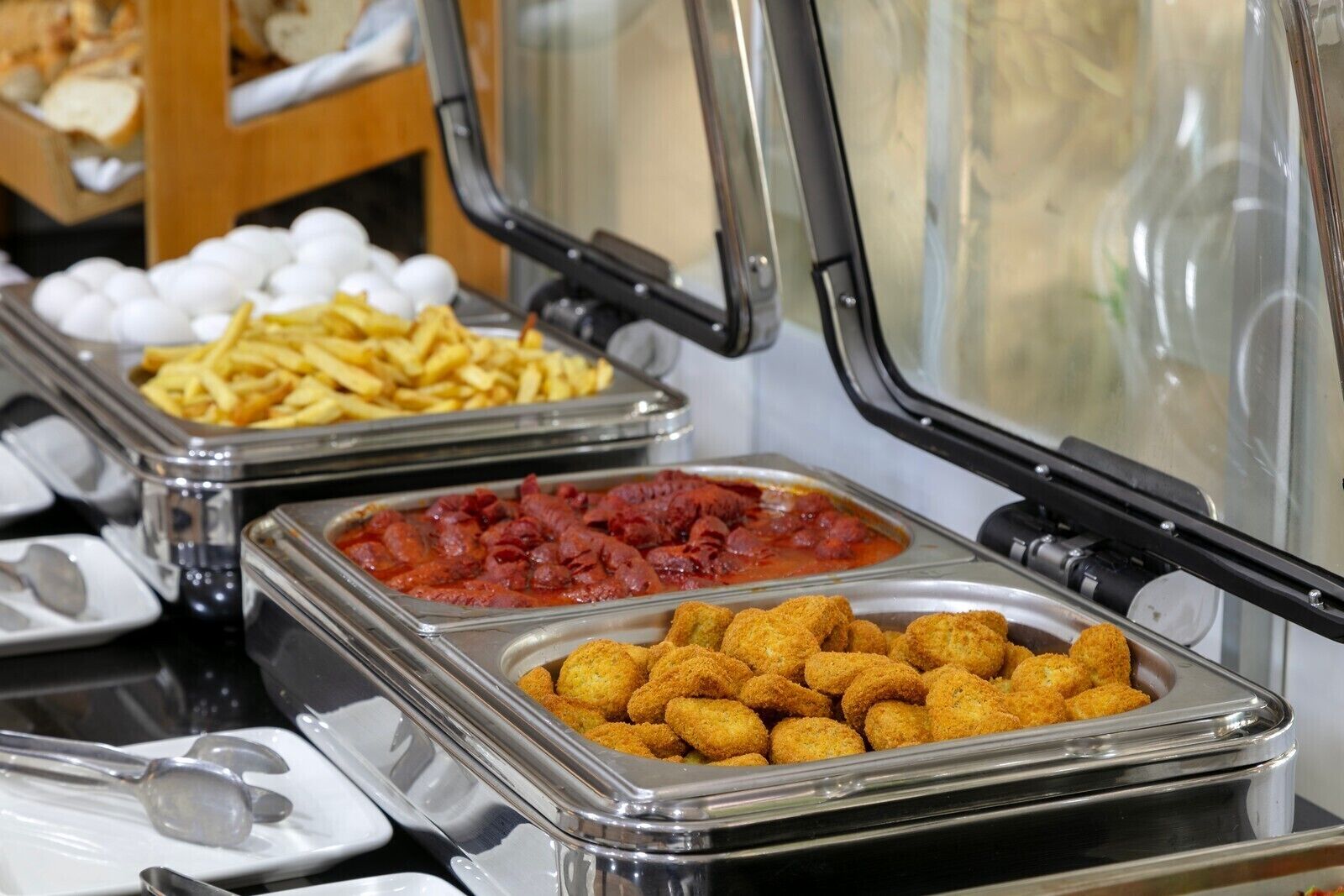 Un buffet proposant divers plats, notamment des frites, une sauce rouge et des petits pains.