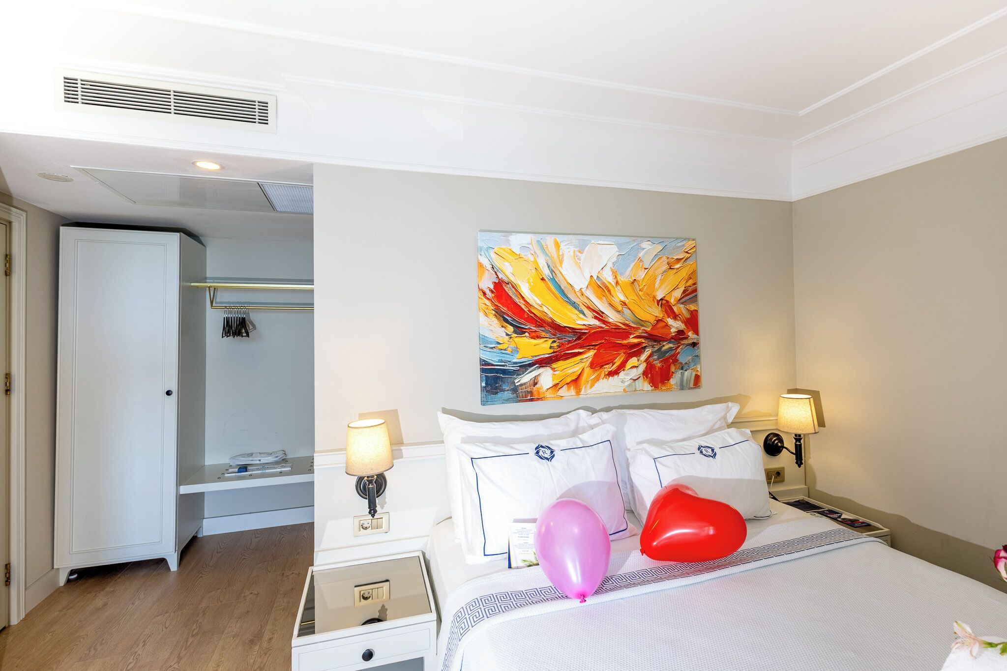 A hotel room with a bed, nightstands, a painting, and a shower area.