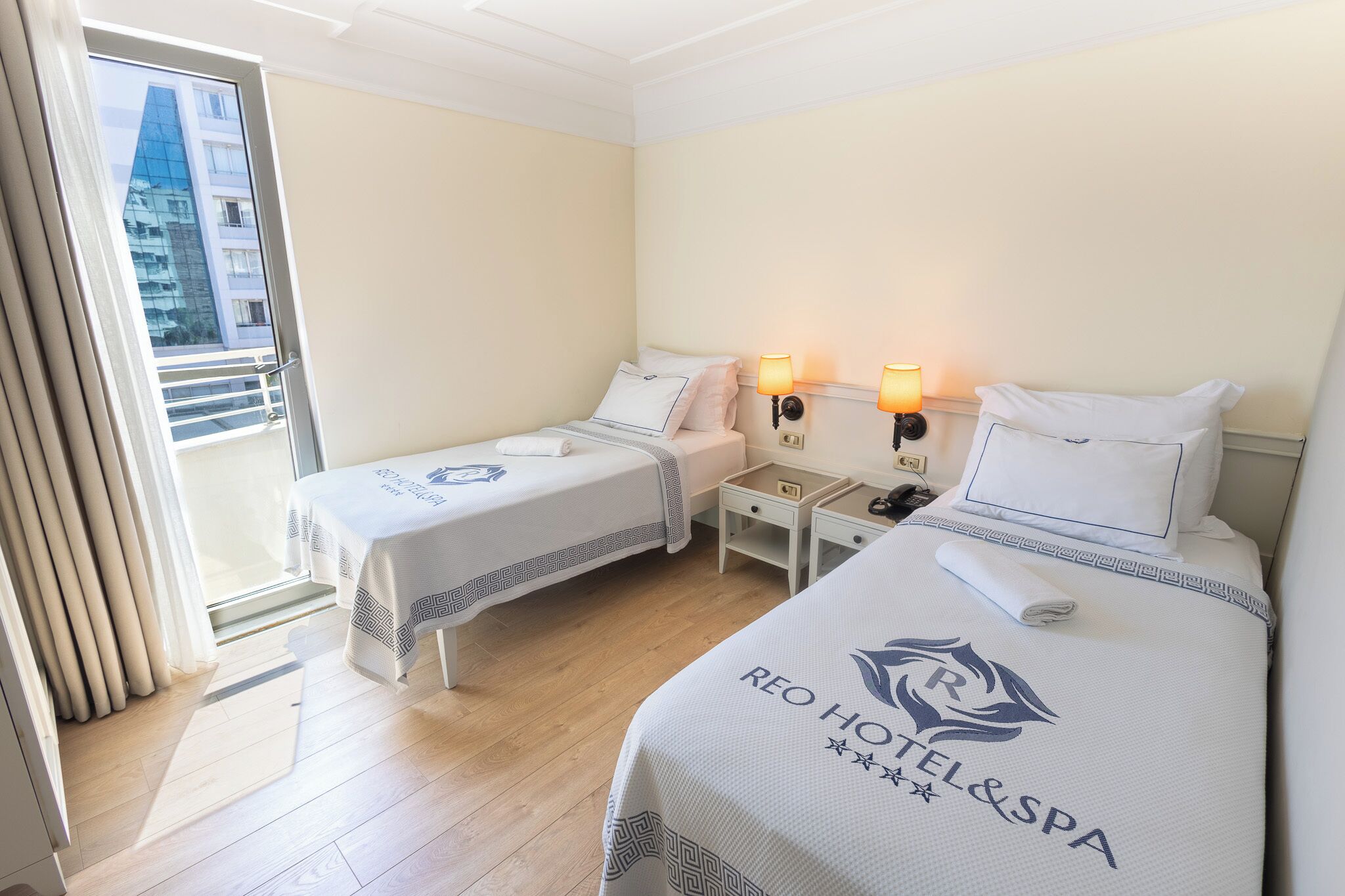 Une chambre d’hôtel avec deux lits, un balcon et une vue sur un immeuble.