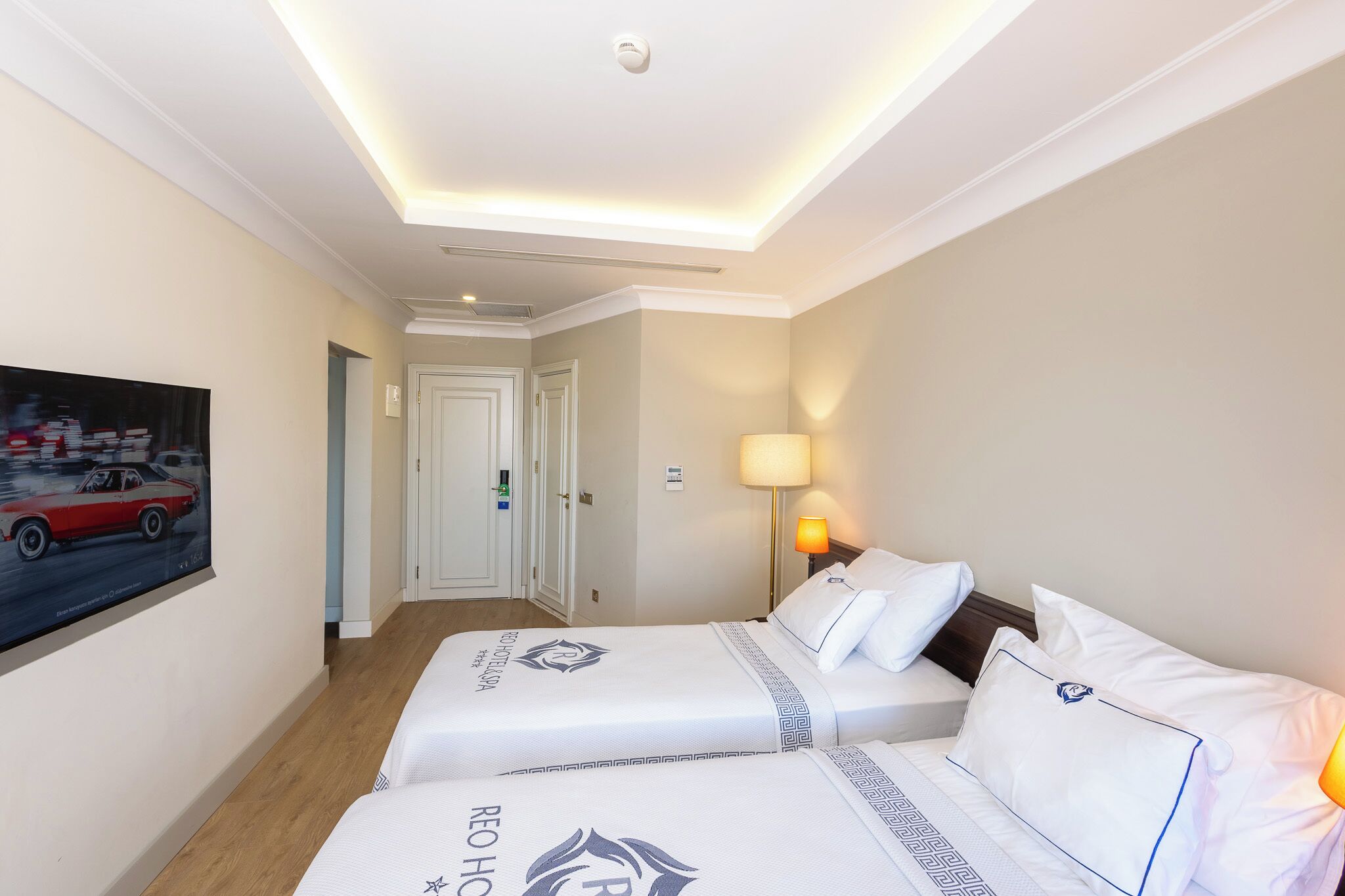 Habitación de hotel con dos camas, un cuadro en la pared, una lámpara y una luz en el techo.