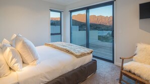 Un dormitorio con una cama, una silla y un ventanal con vistas a la montaña.