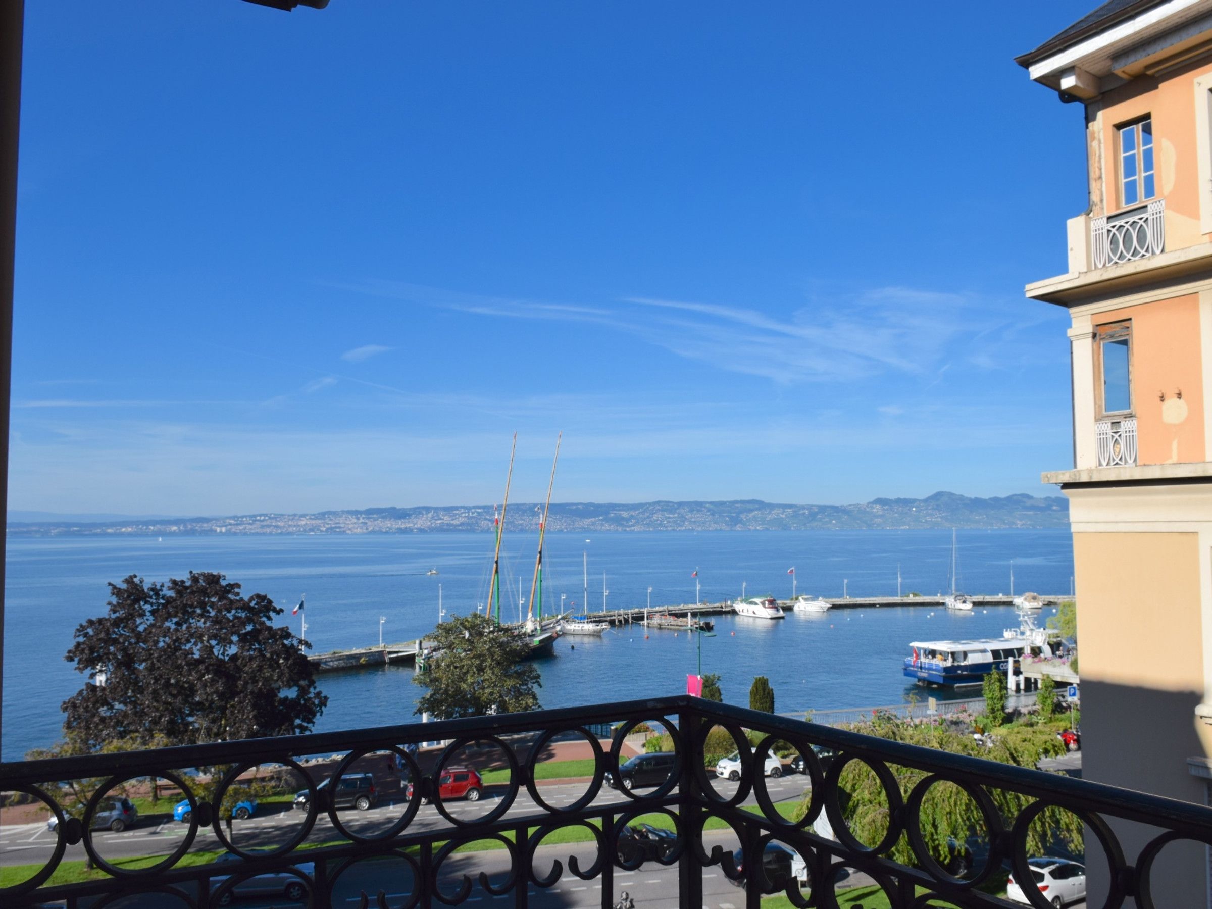 A balcony with a view of a marina, boats, and a distant cityscape.