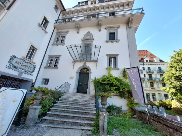 A historic building with a grand entrance, a staircase leading to the main door, and a sign indicating the name 'ANTIQUEITES'.