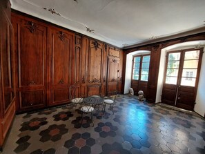 A room with wooden paneling, a hexagonal patterned floor, and a door with glass panes.