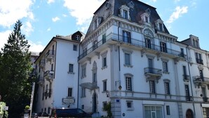 Ein großes, historisches Gebäude mit mehreren Etagen, klassischen architektonischen Details und einem markanten Balkon.