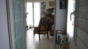 Une pièce comprenant une chaise, une bibliothèque et une porte donnant sur une autre pièce.