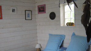 Une chambre à coucher avec un lit, des oreillers, une table de chevet, une lampe et une fenêtre donnant sur un paysage verdoyant.