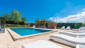 A swimming pool with lounge chairs and a wooden structure in the background.