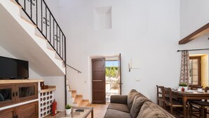 A spacious living area with a sofa, a coffee table, a TV, and a staircase.