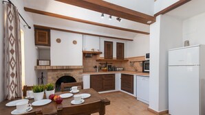 A compact kitchen with a dining area, featuring a brick fireplace, wooden cabinets, and a white refrigerator.