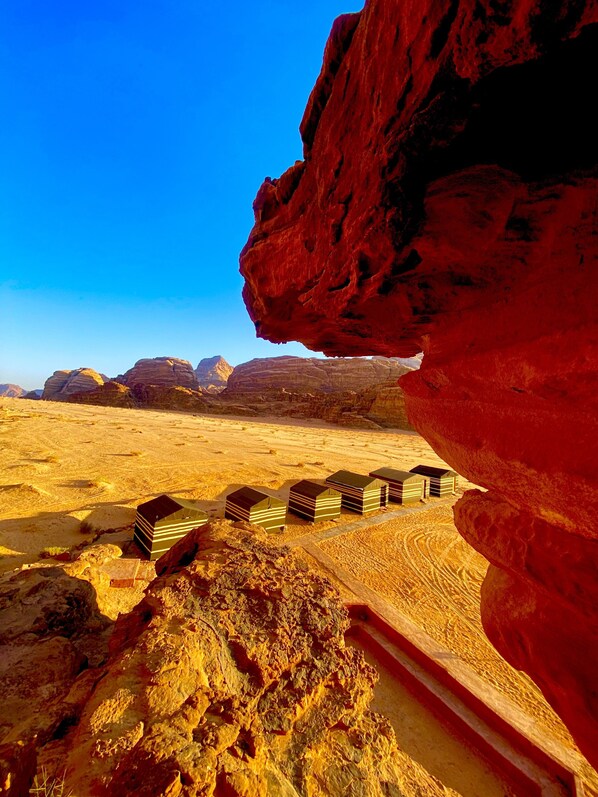 A desert landscape with a prominent red rock formation and a series of stacked structures in the foreground. - Wadi Rum Memories Camp (Wadi Rum)