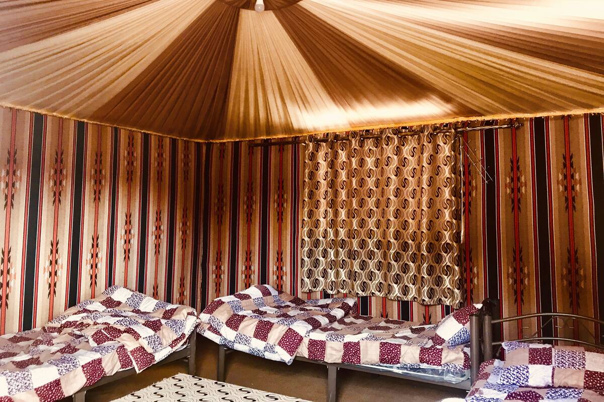 Une chambre avec deux lits, des rideaux à rayures et un baldaquin à motifs.