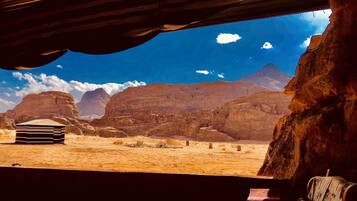 A desert landscape with mountains, a small building, and a rustic interior with a couch and a table.