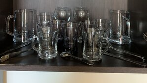 Et køkken med træbordplade, vask og et skab med glas og tallerkener.