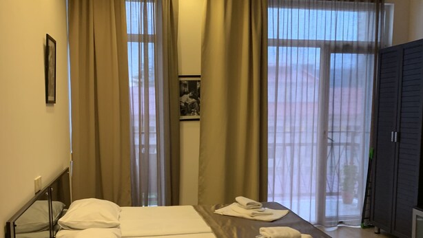 Et lille værelse med køjeseng, et skrivebord og et vindue med gardiner.