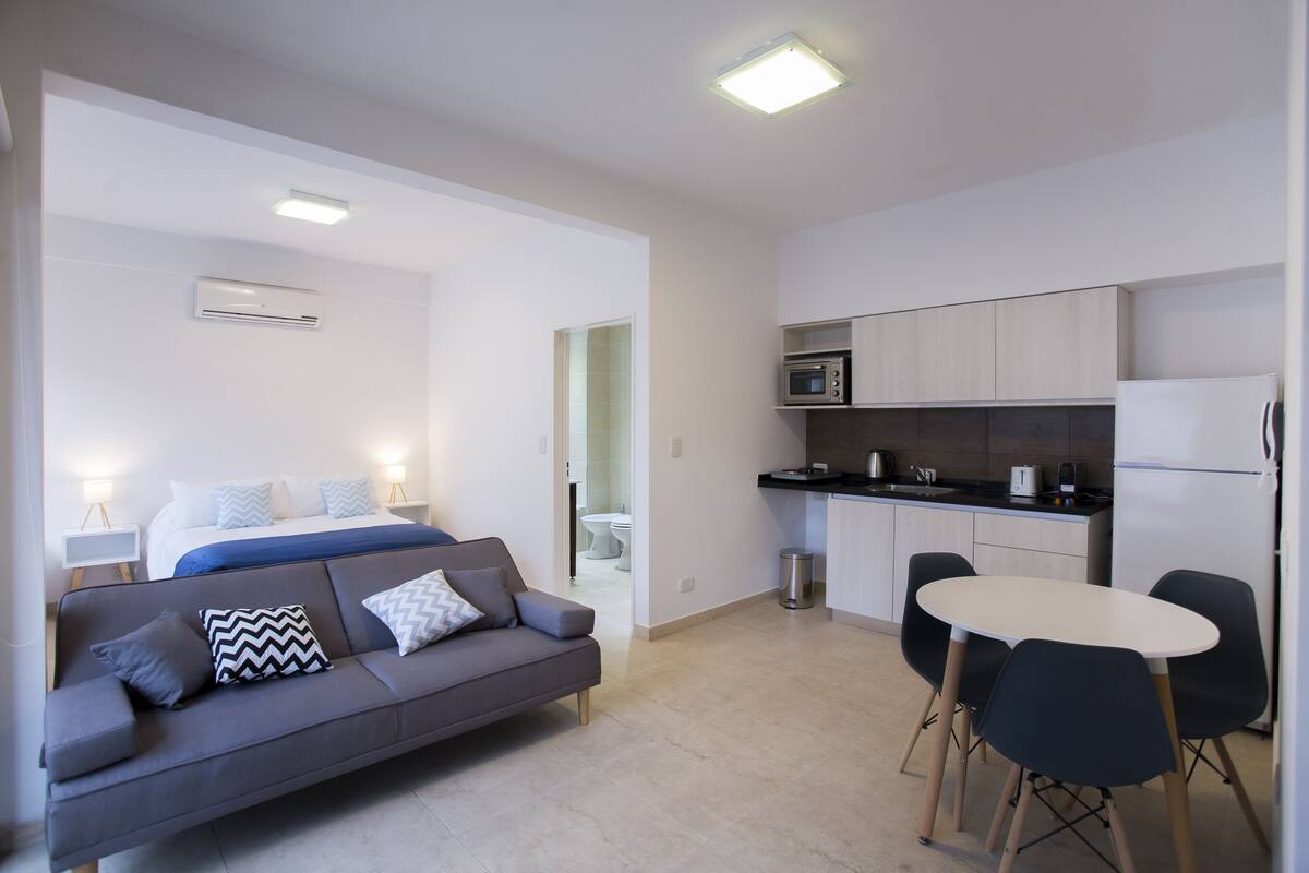A modern apartment with a living area, kitchenette, and a bedroom.