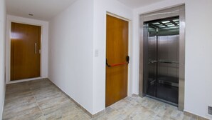 A hallway with two wooden doors and a metallic elevator. - TPYN Palermo (Buenos Aires)